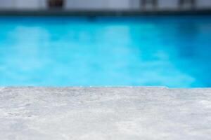 Empty grey ceramic table top and blurred swimming pool in tropical resort in summer banner background photo