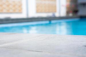 Empty grey ceramic table top and blurred swimming pool in tropical resort in summer banner background photo