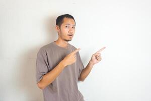 Young Adult Asian men pointing finger to the right with smiling face and exited expression with isolated white background photo