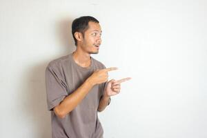 Young Adult Asian men pointing finger to the right with smiling face and exited expression with isolated white background photo