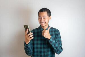 Young asian men is holding smartphone with happy expression in isolated white background photo