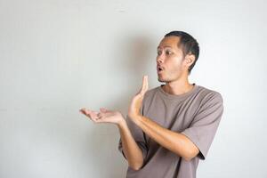 Young Adult Asian men pointing finger to the left with smiling face and exited expression with isolated white background photo