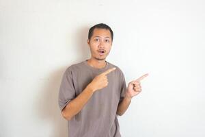 Young Adult Asian men pointing finger to the right with smiling face and exited expression with isolated white background photo