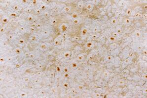 Detailed close-up of a tortilla bread surface showing its unique texture and golden brown spots, perfect for food backgrounds and culinary projects. photo