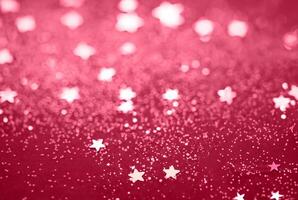 Abstract Glitter Background with Scattered Star Shaped Confetti on a Red Surface photo