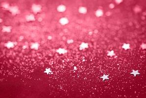 Abstract Glitter Background with Scattered Star Shaped Confetti on a Red Surface photo
