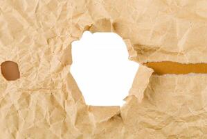 Close-up of crumpled brown paper with a torn hole, creating a frame effect on a white background, ideal for creative design use. photo