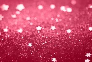 Abstract Glitter Background with Scattered Star Shaped Confetti on a Red Surface photo