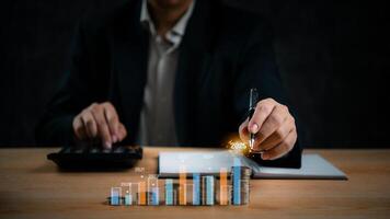Businessman using calculator and pen to draw graphs on table photo
