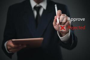 Man in suit holding tablet with approval and rejected text photo
