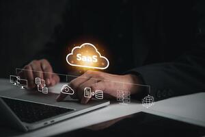 Hand interacting with SaaS icons above laptop, showcasing software as a service concept. Perfect for technology, cloud computing, digital business solutions. photo