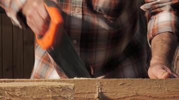 A skilled artisan meticulously saws through timber, showcasing craftsmanship and dedication as the golden afternoon light streams in. close-up video