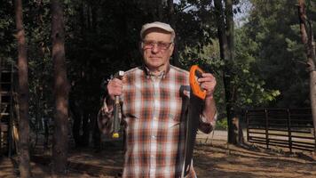 An elderly craftsman demonstrates the tools he uses in his work while building a wooden house. video