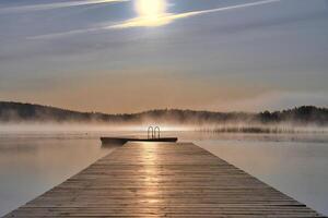 Wooden jetty in the morning at sunrise in the fog, on a Swedish lake. Scandinavian photo