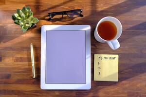 A tidy desk setup with a tablet, coffee, and a todo list for better productivity photo