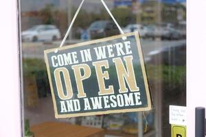 There is an Open and Awesome Sign displayed prominently at a Shop Entrance, attracting customers photo