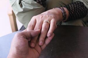 An intimate Romantic Hand Hold adorned with a Wedding Ring in a charming Cafe Setting photo