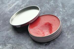 An Open Tin of Vibrant Red and White Ointment Placed Elegantly on a Gray Background Surface photo