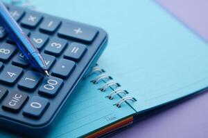 A digital calculator and a notebook are placed on a colorful and vibrant desk surface photo