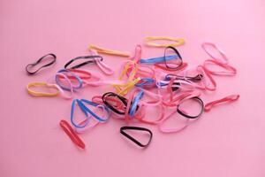 A Colorful and Interesting Assortment of Rubber Bands Displayed on a Pink Background photo