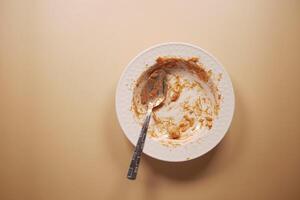 An empty plate with a spoon rests after a delicious, satisfying meal has been enjoyed photo