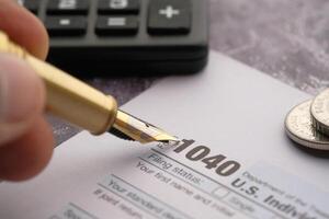 Tax Filing Using Form 1040, a Calculator, and Various Coins Placed on the Table Surface photo