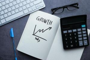 The concept of business growth is illustrated with the use of a calculator and a notebook photo