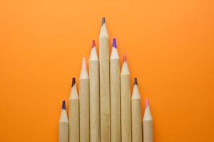 A Variety of Colorful Pencils Neatly Arranged in a Bright Pattern Set Against an Orange Background photo