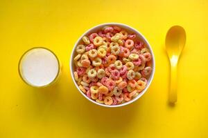 A Vibrant and Colorful Breakfast Cereal Served with Milk on a Bright Yellow Background photo