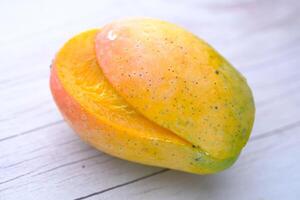 A Fresh and Ripe Mango Placed Beautifully on a Wooden Surface for Display and Enjoyment photo
