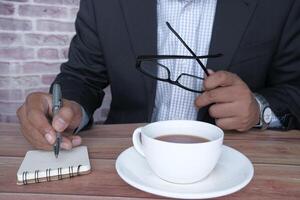 A Professional Man Engaged in Writing Notes While Enjoying Coffee in a Stylish Office Setting photo