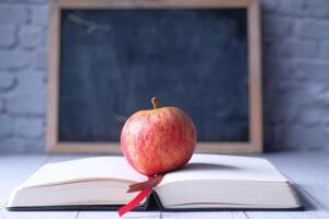 An apple on an open book with a chalkboard background evokes education and nostalgia photo