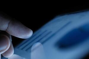 A closeup view of a finger engaging with a digital screen amidst a low light environment photo