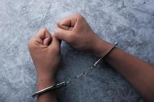 Hands Being Restrained in Handcuffs on a Gray Surface, Symbolizing Authority and Justice photo