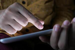 A person is engaging with a tablet screen while in a dimly lit environment for various purposes photo