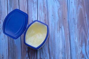 An Open Container of Soft Butter Resting on a Rustic Wooden Surface in the Kitchen photo