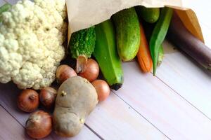 A Variety of Fresh Organic Vegetables Arranged in a Paper Bag on a Rustic Background photo