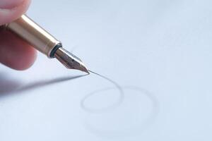 Closeup view of a Fountain Pen skillfully Creating Elegant Calligraphy on a White Sheet of Paper photo