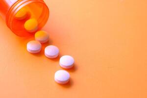 Spilled Pills from an Orange Prescription Bottle on a Bright and Colorful Background photo