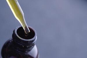 Closeup of a pipette with liquid above a brown bottle, showcasing its features and purpose photo