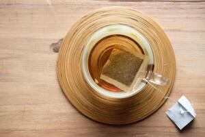 A Tea Bag Infusing Slowly in a Beautiful Glass Teapot, Resting on a Rustic Wooden Surface photo