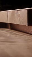 Unrecognizable man working with professional, electric circular saw, making a precise cut along the guide on a wooden surface. Tool is connected to a dust extraction system. Woodworking workshop video