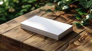 A stack of white business cards sits on a wooden table photo