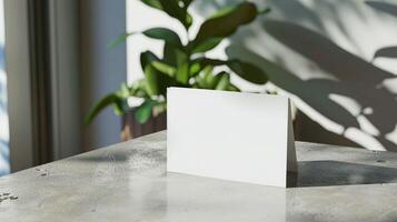 A white card is sitting on a table in front of a plant photo