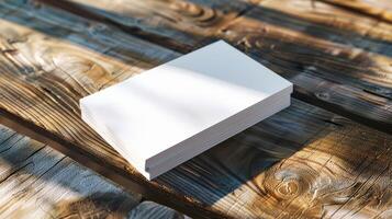 A stack of white business cards sits on a wooden table photo