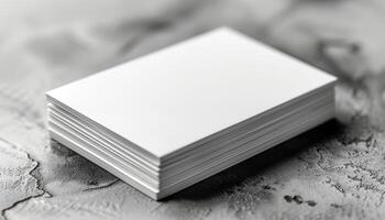 A stack of white business cards sits on a grey surface photo