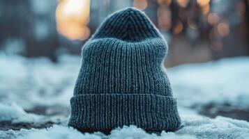 A gray knit hat is sitting on top of a snowy surface photo