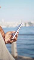 Vertical Shot of A Person Using a Smartphone by the Tranquil Waters Edge, Captivating Scene video
