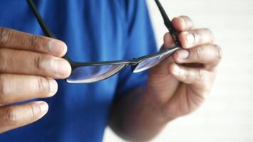 An individual in a bright indoor setting is adjusting their glasses while smiling contentedly video