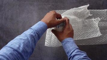 Carefully wrapping hands around an item with bubble wrap to ensure safe shipping and protection video